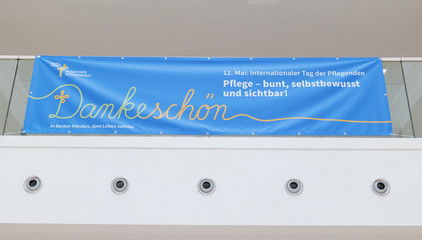 Ein großes blaues Banner hängt in der Eingangshalle des Albertinen Krankenhauses in Hamburg mit der Aufschrift Dankeschön", "12. Mai: Internationaler Tag der Pflegenden" und "Pflege - bunt, selbstbewusst und sichtbar!" am Internationalen Tag der Pflegenden.